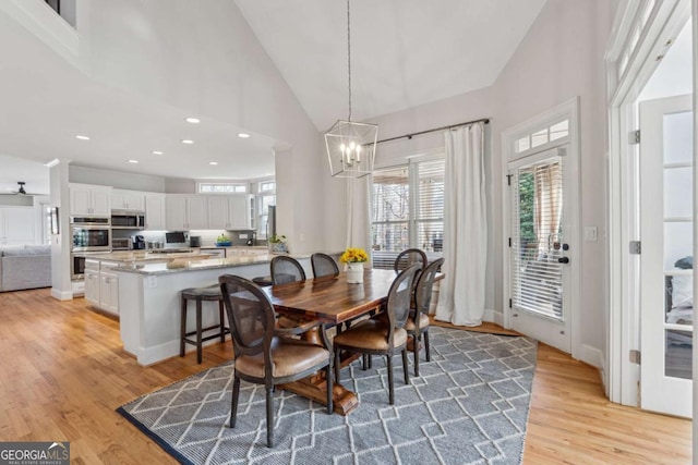 dining area featuring a chandelier, high vaulted ceiling, light wood-type flooring, and recessed lighting