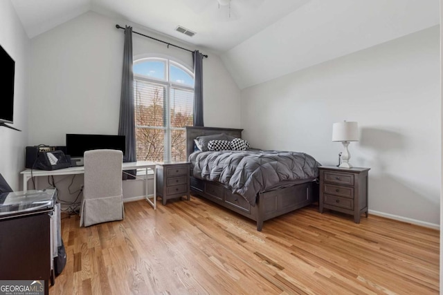 bedroom featuring lofted ceiling, light wood-style flooring, a ceiling fan, visible vents, and baseboards