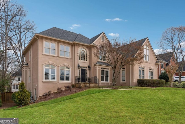 view of front of house with a front lawn, fence, and stucco siding