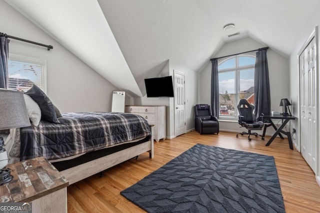 bedroom with lofted ceiling, baseboards, visible vents, and light wood finished floors