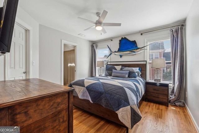 bedroom with ceiling fan, light wood-style flooring, and baseboards