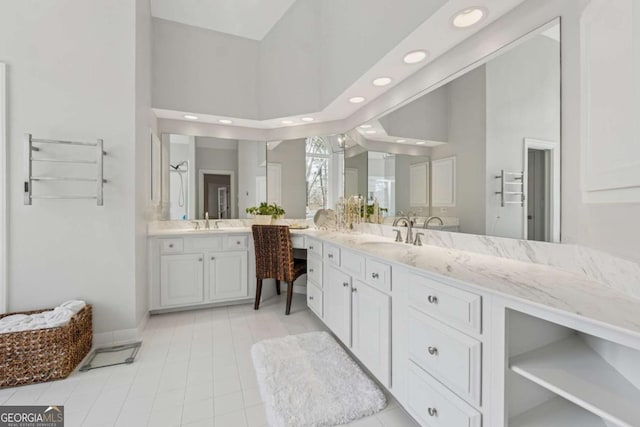 bathroom with recessed lighting, baseboards, vanity, and a high ceiling