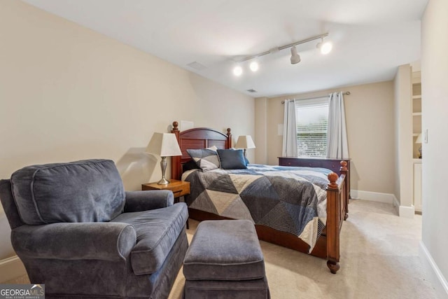 bedroom with light carpet, rail lighting, visible vents, and baseboards