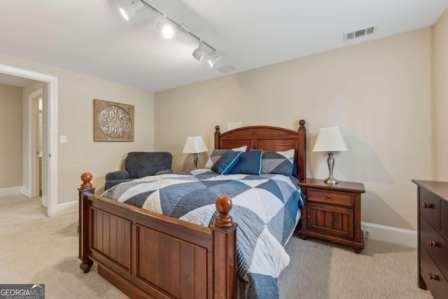 bedroom featuring baseboards, track lighting, visible vents, and light colored carpet