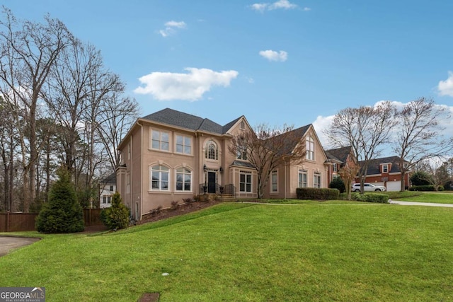 view of front of home featuring stucco siding, fence, and a front yard