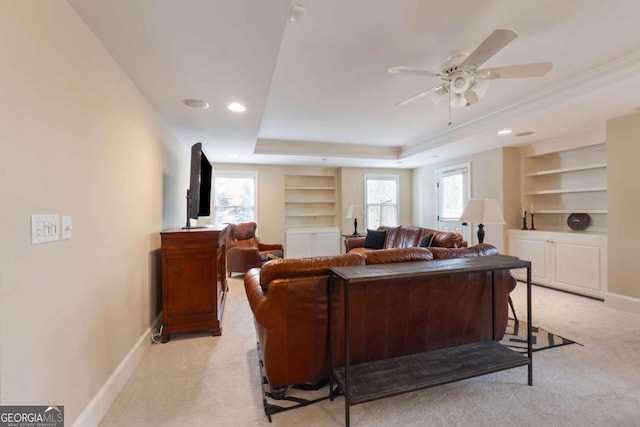 living area featuring baseboards, a tray ceiling, plenty of natural light, and light colored carpet