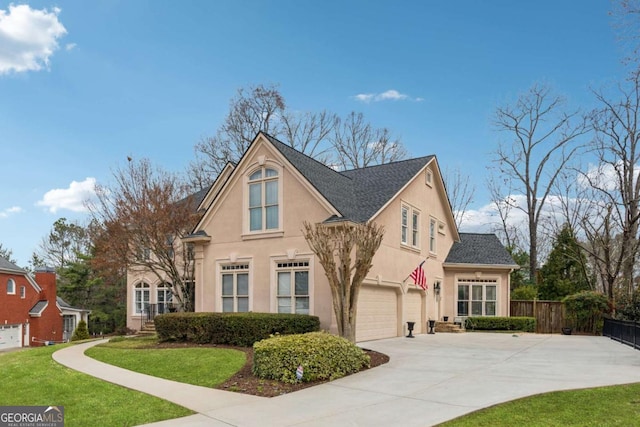 traditional-style home featuring a garage, fence, concrete driveway, stucco siding, and a front yard