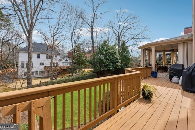 wooden terrace featuring a ceiling fan, a yard, and area for grilling