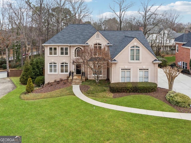 traditional-style home with a front yard, roof with shingles, a chimney, and stucco siding