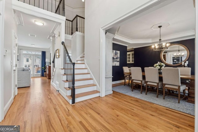 entryway with a notable chandelier, stairway, ornamental molding, wood finished floors, and baseboards