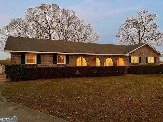 ranch-style house featuring brick siding and a front lawn