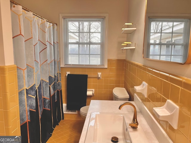 bathroom with wainscoting, toilet, tile walls, and a healthy amount of sunlight