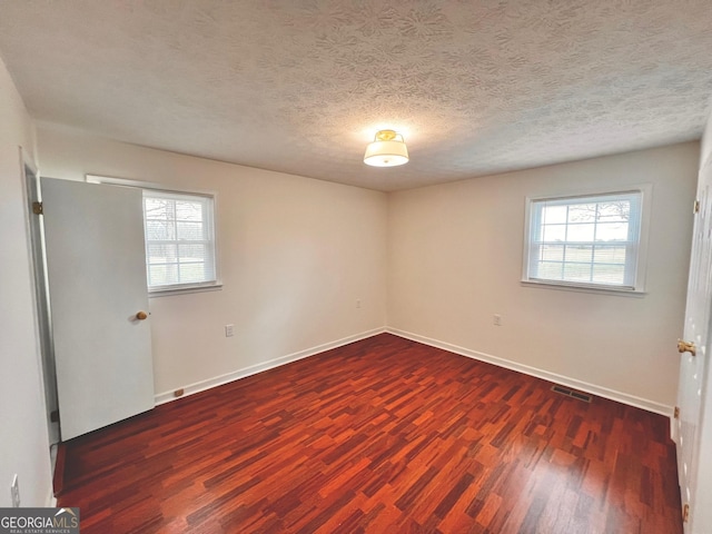 empty room featuring baseboards, visible vents, a wealth of natural light, and wood finished floors
