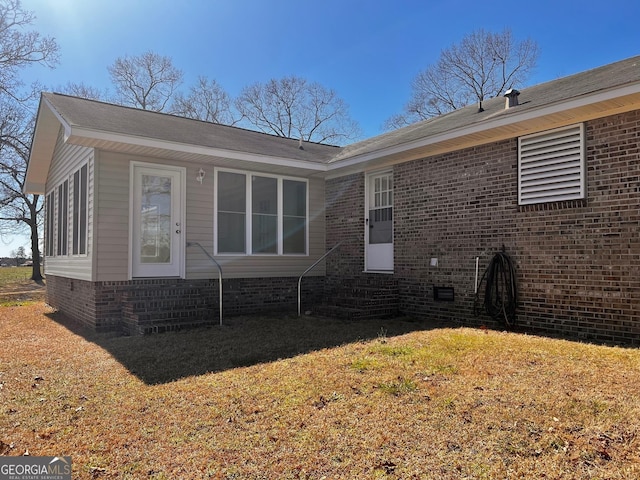 back of property with entry steps, crawl space, brick siding, and a lawn