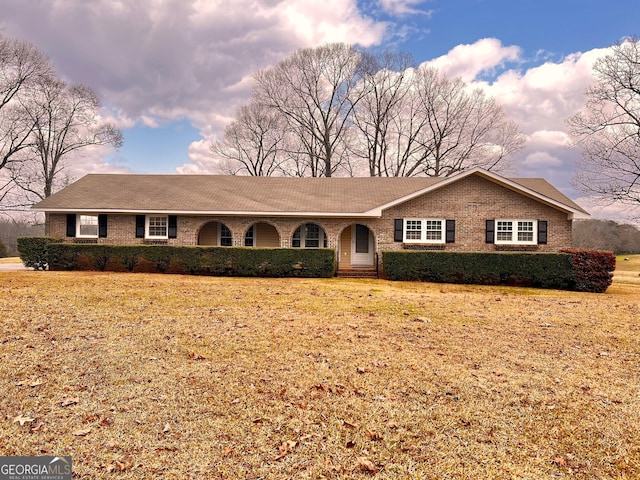 ranch-style house with a front lawn, brick siding, and roof with shingles