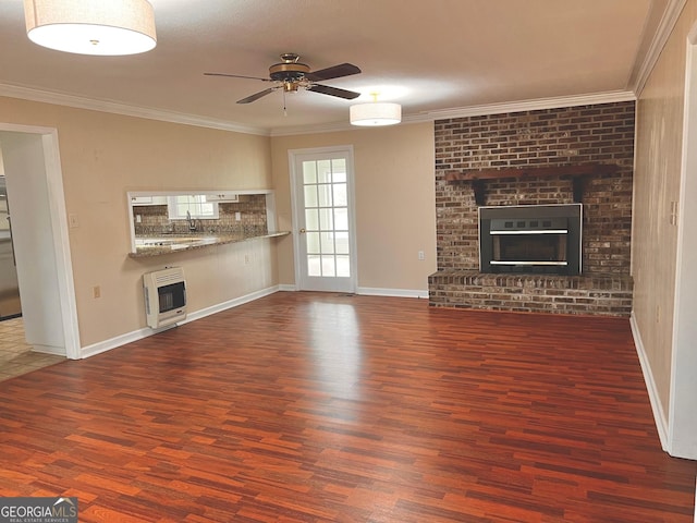 unfurnished living room with a ceiling fan, wood finished floors, heating unit, crown molding, and a fireplace