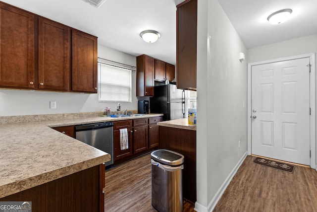 kitchen featuring dark wood-style flooring, baseboards, light countertops, freestanding refrigerator, and dishwasher