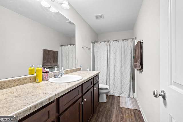 bathroom with toilet, wood finished floors, vanity, visible vents, and a shower with curtain