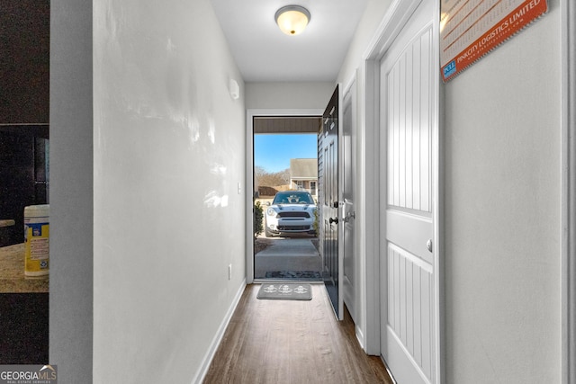 corridor featuring dark wood-type flooring and baseboards