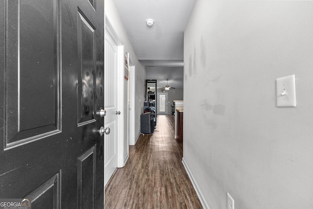 hallway featuring baseboards and dark wood-type flooring