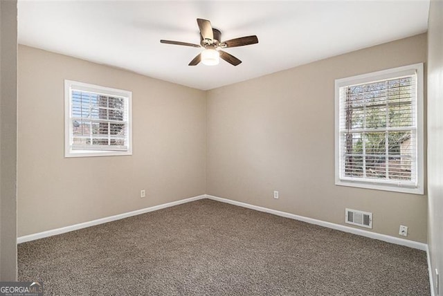 carpeted spare room featuring a wealth of natural light, visible vents, and baseboards