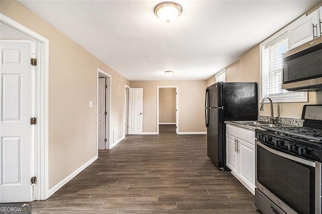 kitchen with stainless steel appliances, white cabinetry, a sink, and dark wood-style floors