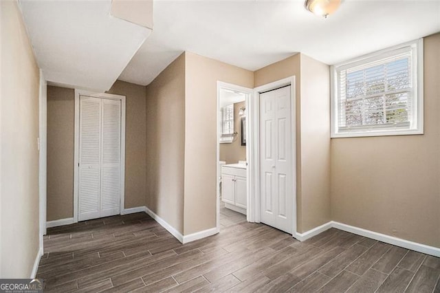 unfurnished bedroom featuring baseboards, dark wood-type flooring, and ensuite bathroom