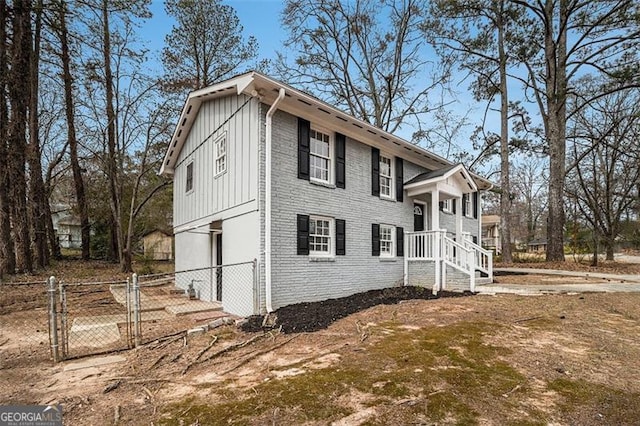 view of side of home with a gate, fence, board and batten siding, and brick siding