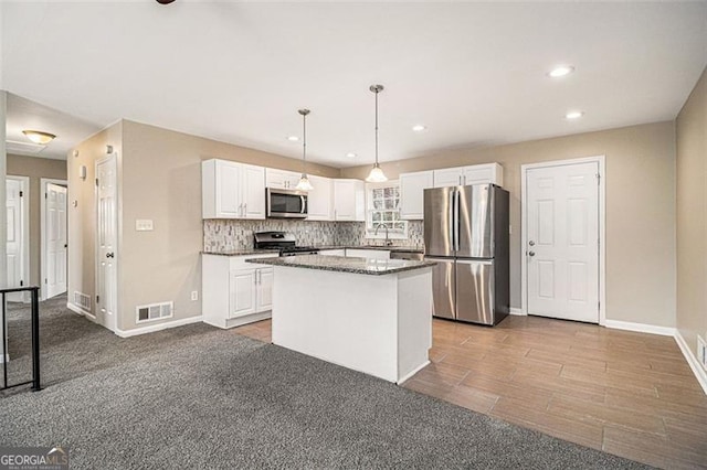 kitchen with visible vents, appliances with stainless steel finishes, a center island, white cabinetry, and backsplash