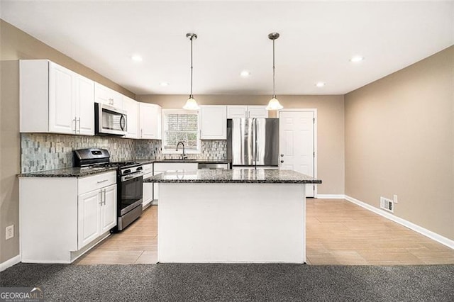 kitchen featuring stainless steel appliances, a kitchen island, visible vents, white cabinetry, and backsplash