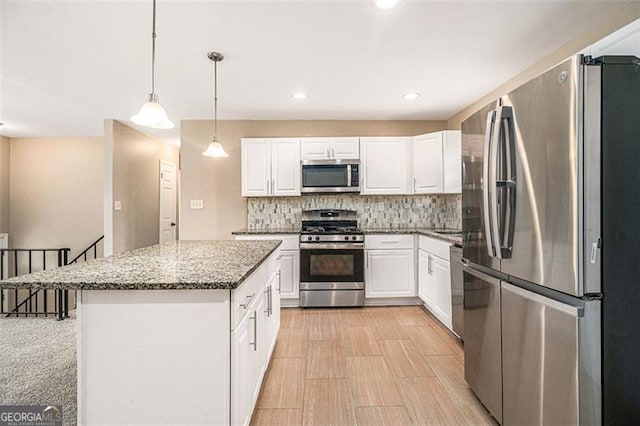 kitchen featuring light stone counters, a center island, stainless steel appliances, tasteful backsplash, and white cabinets