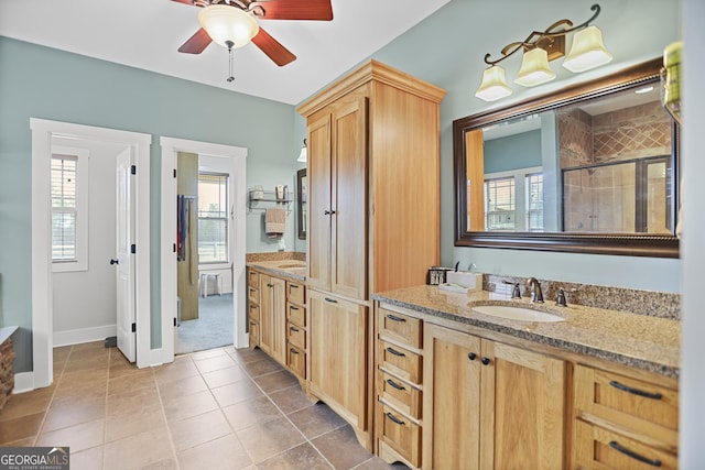 bathroom with ceiling fan, a sink, tile patterned floors, double vanity, and a stall shower