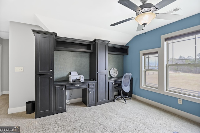 home office featuring lofted ceiling, ceiling fan, light carpet, visible vents, and baseboards