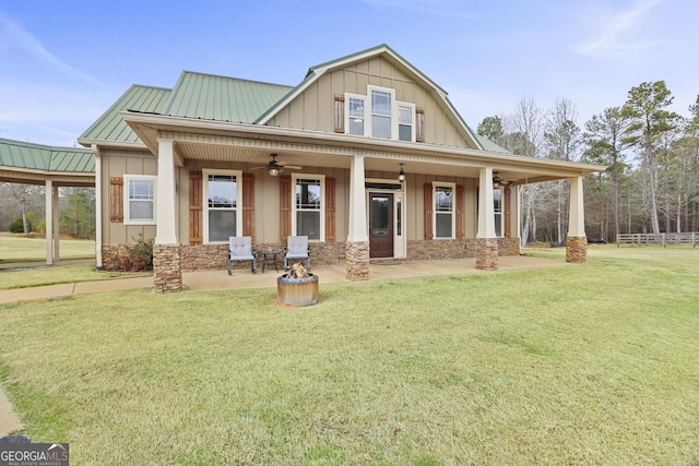 view of front of property with metal roof, board and batten siding, a front yard, and a ceiling fan