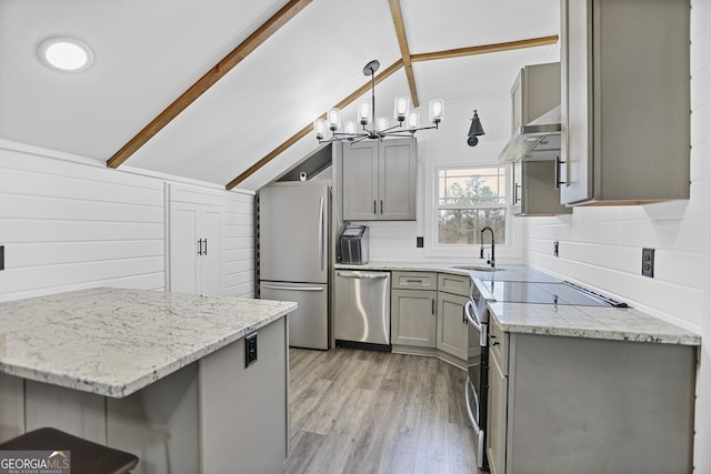 kitchen featuring lofted ceiling with beams, light stone counters, gray cabinetry, stainless steel appliances, and wall chimney range hood