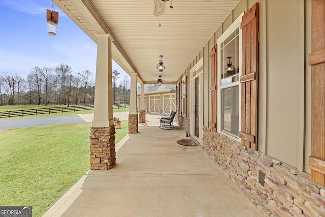 view of patio / terrace with ceiling fan, a porch, and fence