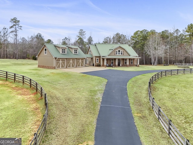 farmhouse-style home featuring metal roof, aphalt driveway, fence, and a front lawn