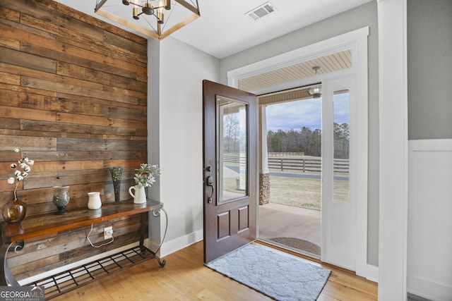 entrance foyer featuring baseboards, light wood-style flooring, visible vents, and a notable chandelier