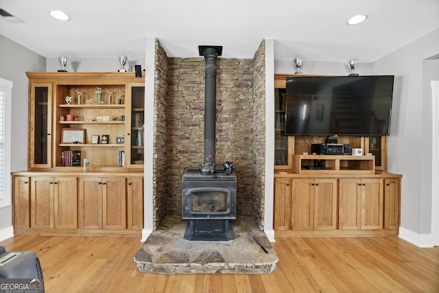 living room with visible vents, recessed lighting, a wood stove, and light wood-style floors