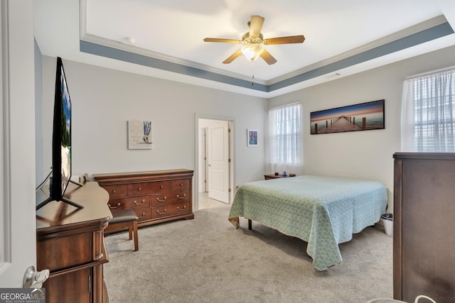 bedroom featuring ornamental molding, ceiling fan, a tray ceiling, and carpet