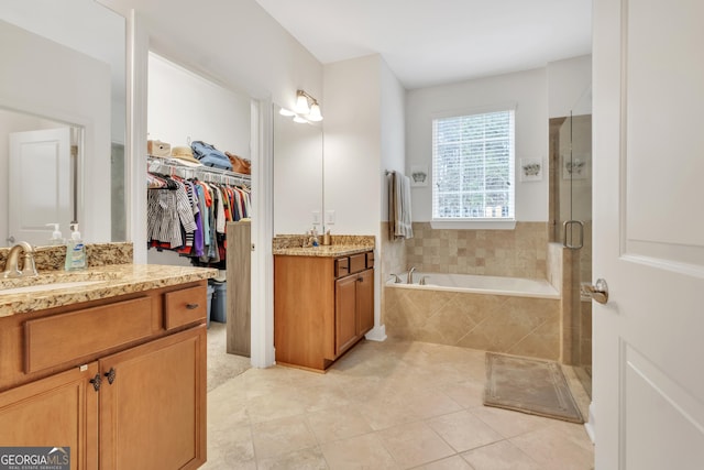 full bath with two vanities, tile patterned floors, a sink, a shower stall, and a bath