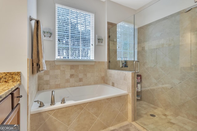 bathroom featuring a stall shower, a garden tub, and vanity