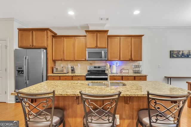 kitchen with visible vents, decorative backsplash, appliances with stainless steel finishes, crown molding, and a sink