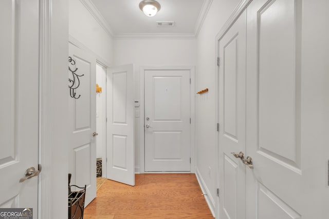 hall featuring visible vents, crown molding, and light wood finished floors