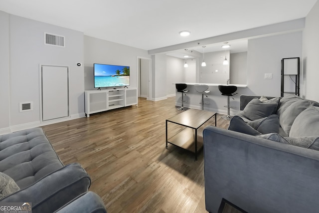 living room with wood finished floors, visible vents, and baseboards