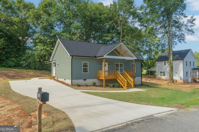 view of front of property featuring driveway, roof with shingles, crawl space, covered porch, and a front yard