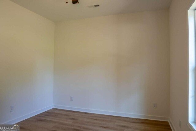 unfurnished room featuring visible vents, baseboards, and wood finished floors