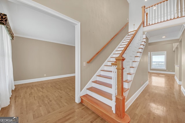 stairs with baseboards, wood finished floors, and crown molding