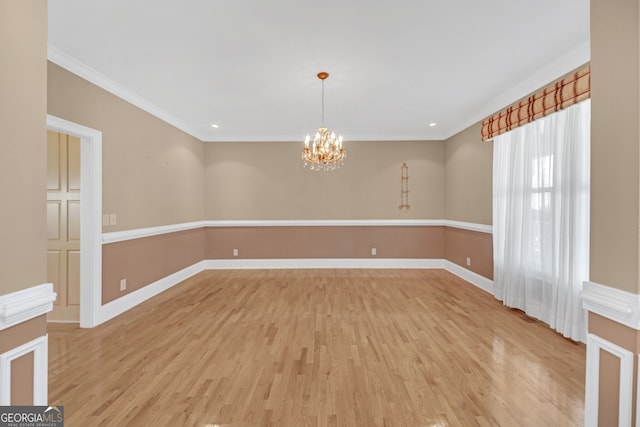 unfurnished room with light wood-style floors, ornamental molding, and an inviting chandelier