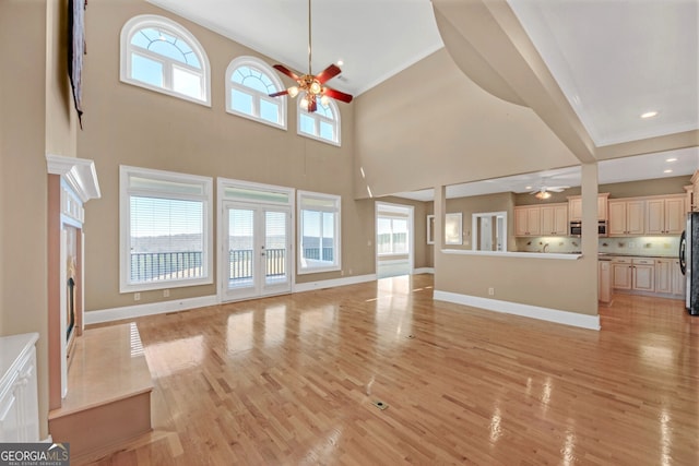 unfurnished living room featuring light wood-style floors, baseboards, and a ceiling fan